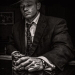 Man in fedora and suit holding drink