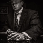 Man in fedora and suit holding drink