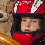 Child in red racing helmet with teddy bear