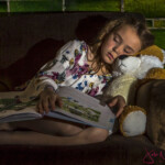 Girl asleep on couch with book and teddy