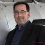 Smiling man in glasses standing by airplane