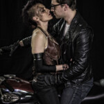Couple embracing beside motorcycle in leather outfits
