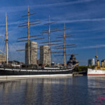 Two historic ships docked by city skyline
