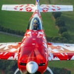 Red star-patterned aerobatic plane over fields