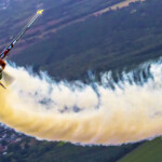 Aerobatic plane trailing smoke over farmland