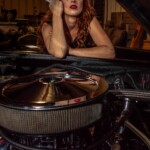 Red-haired woman holding wrench over car engine