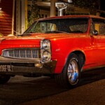 Red vintage Pontiac parked on street at night